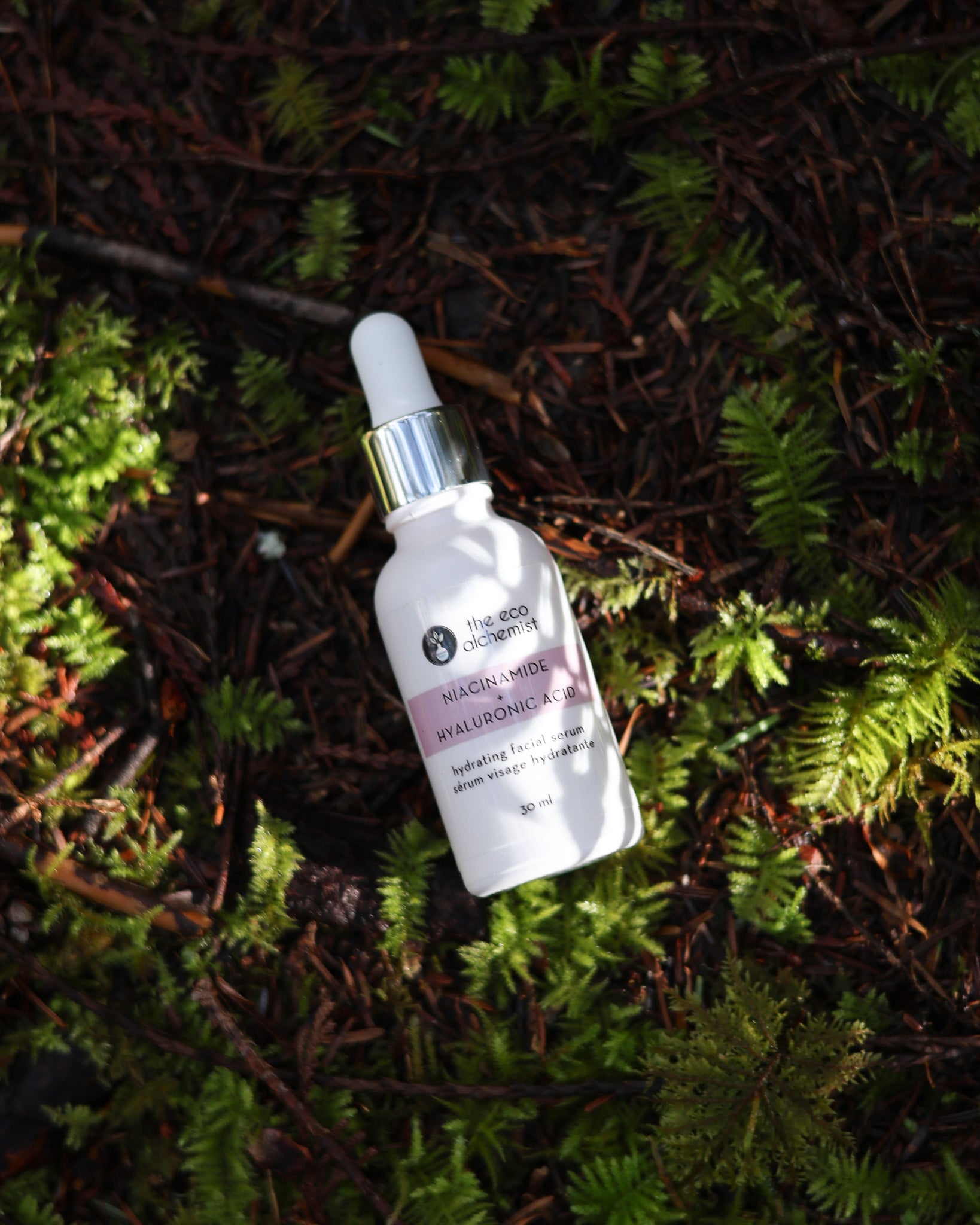 Niacinamide + Hyaluronic Acid Hydrating Facial Serum in the forest with sun shining through the trees