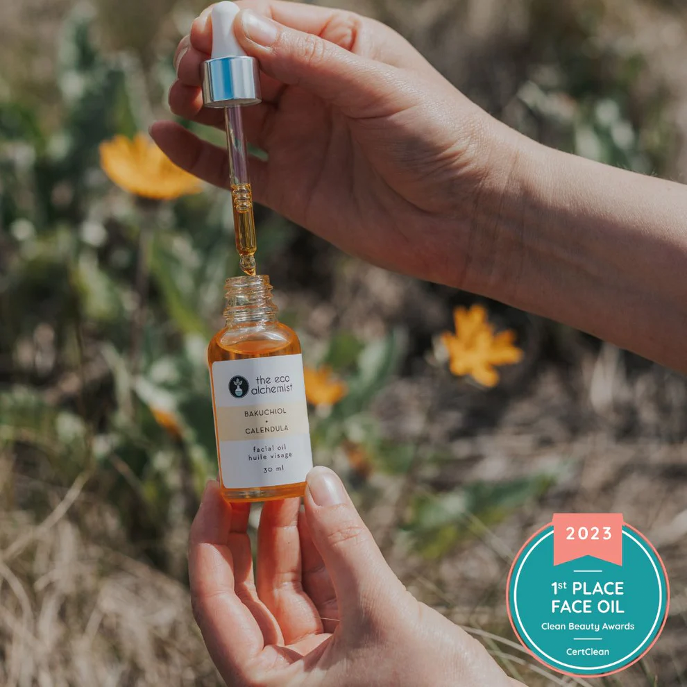 A dropper bottle of Bakuchiol + Calendula Bio-Retinol Facial Oil being held by a hand, with a background of natural elements.